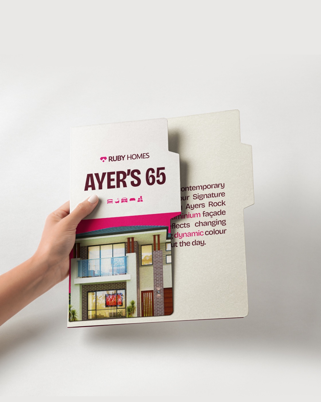 Ayer's 65 property brochure held in hand, opening to reveal the home render